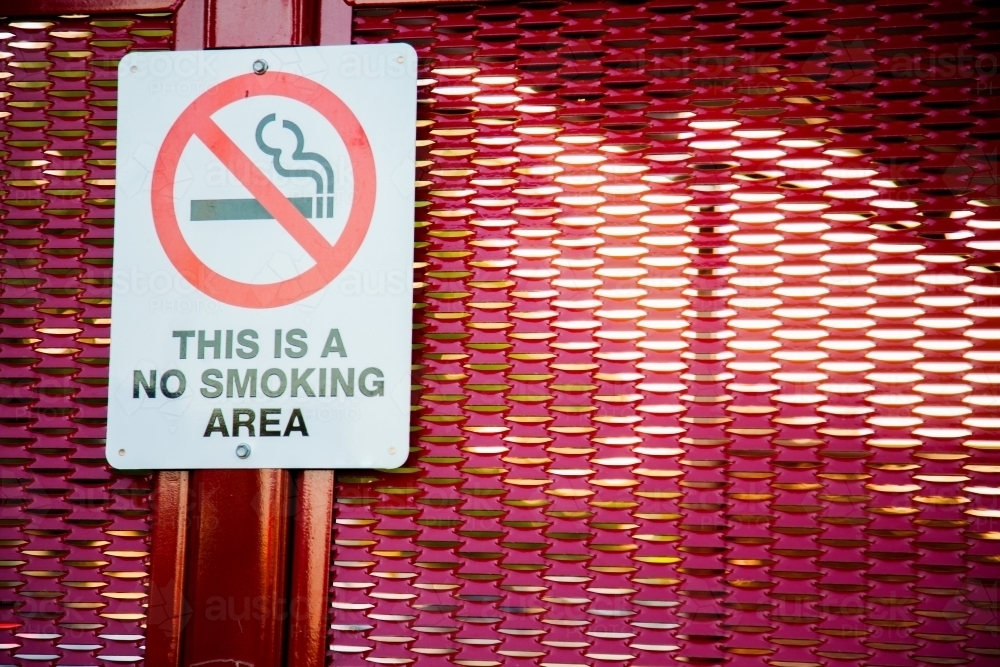 This is a no smoking area sign on red bus stop shelter - Australian Stock Image