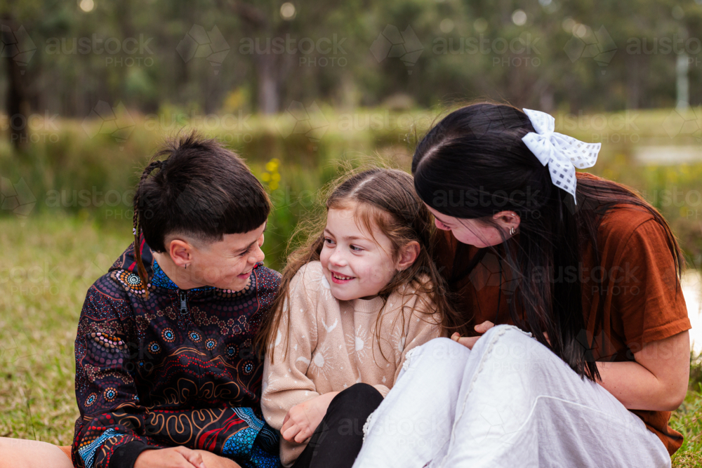 Three aboriginal kids hugging and smiling together outside - Australian Stock Image