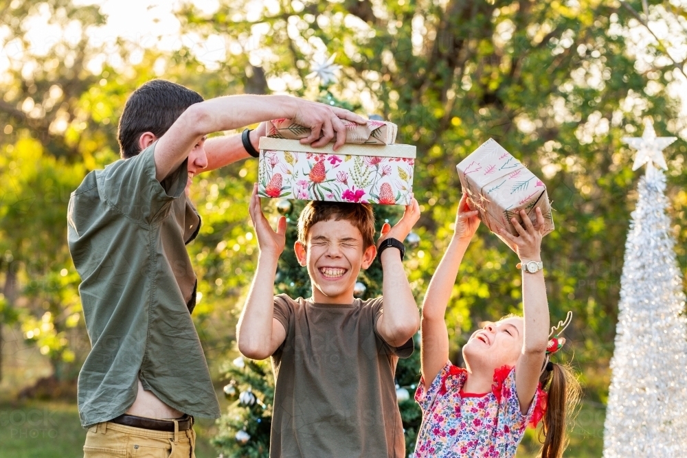 Three Aussie kids being silly with Christmas gifts in rural Australia - Australian Stock Image