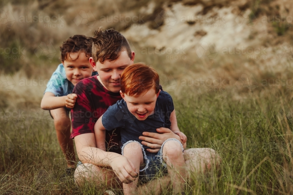 Three brothers sitting together on a rock in the Australian bush - Australian Stock Image