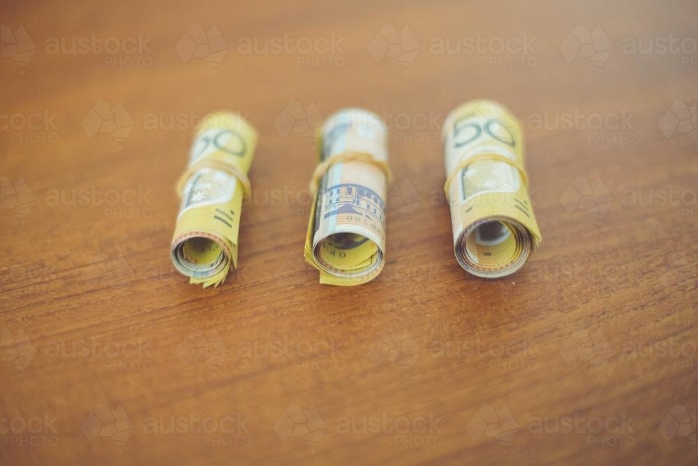 Three bundles of rolled up 50 dollar notes - Australian Stock Image