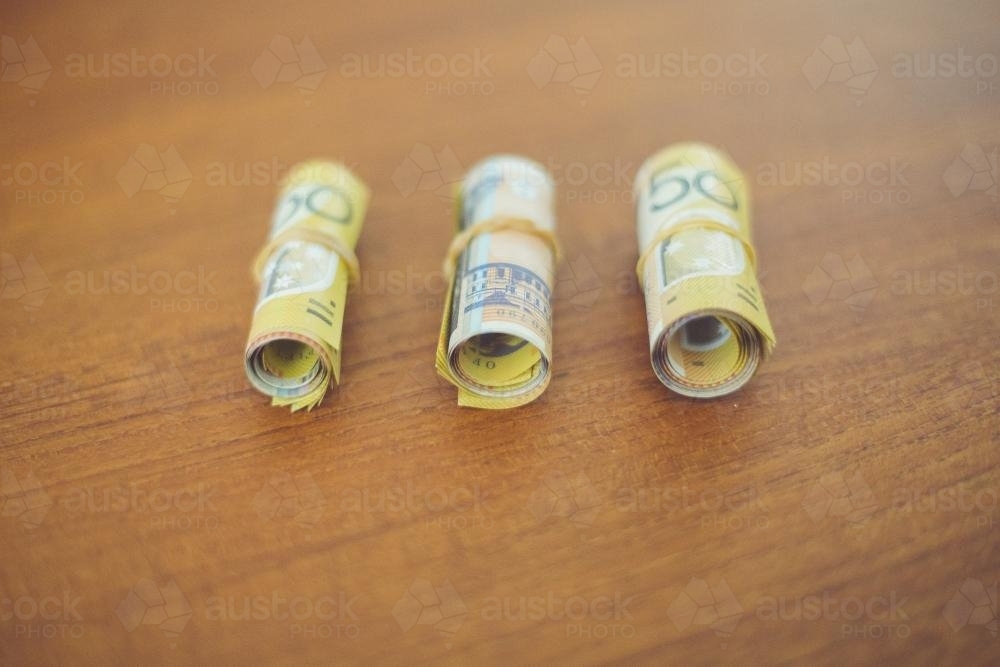Three bundles of rolled up 50 dollar notes - Australian Stock Image