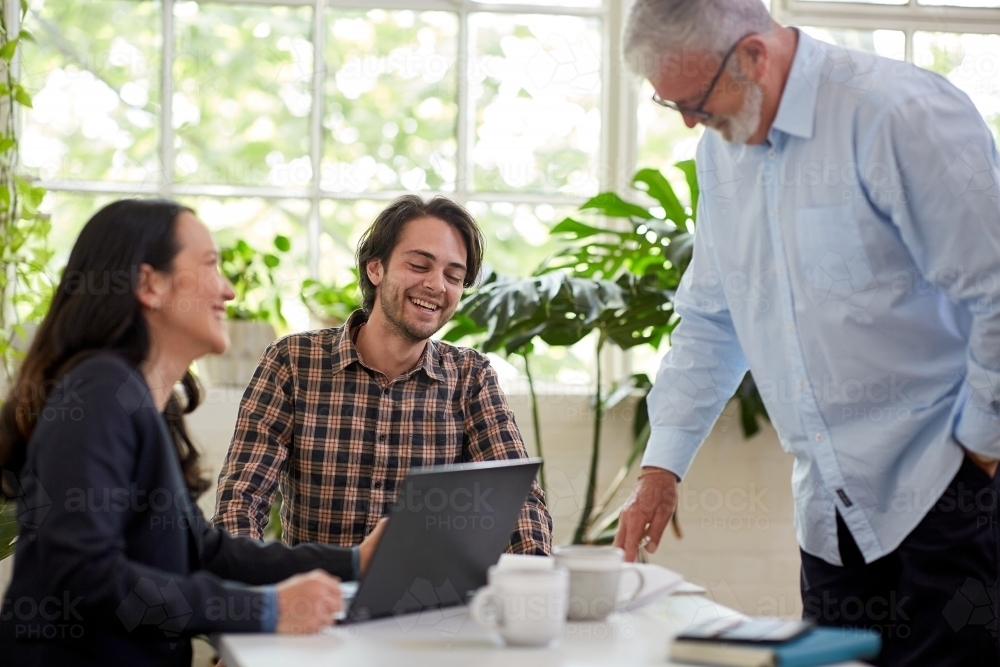 Three business people chatting, working in a studio office - Australian Stock Image