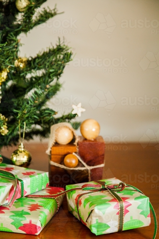 Three Christmas gifts tide up with string under a small decorated tree - Australian Stock Image
