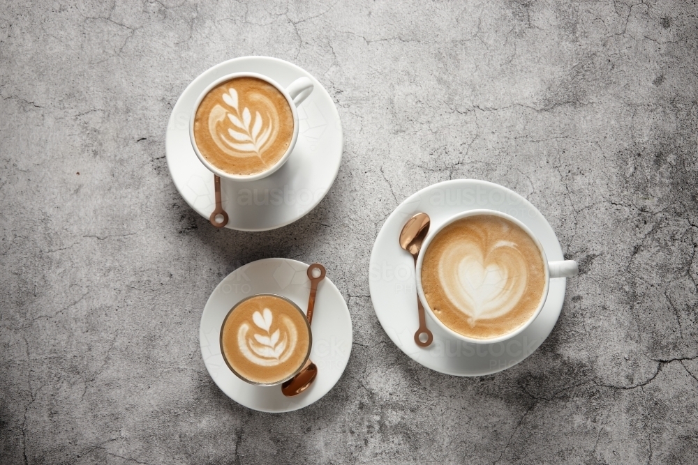 Three coffees on saucers with teaspoons - Australian Stock Image
