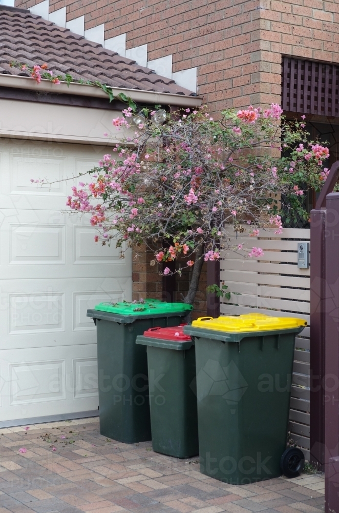 Image of Three coloured garbage bins in a driveway - Austockphoto