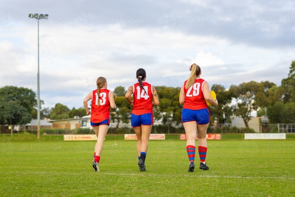 three female footballers running onto playing field - Australian Stock Image