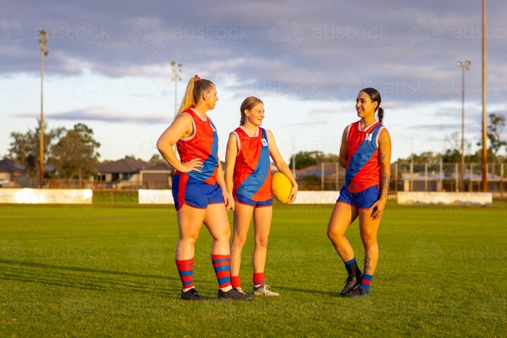 Three female footballers standing on oval - Australian Stock Image