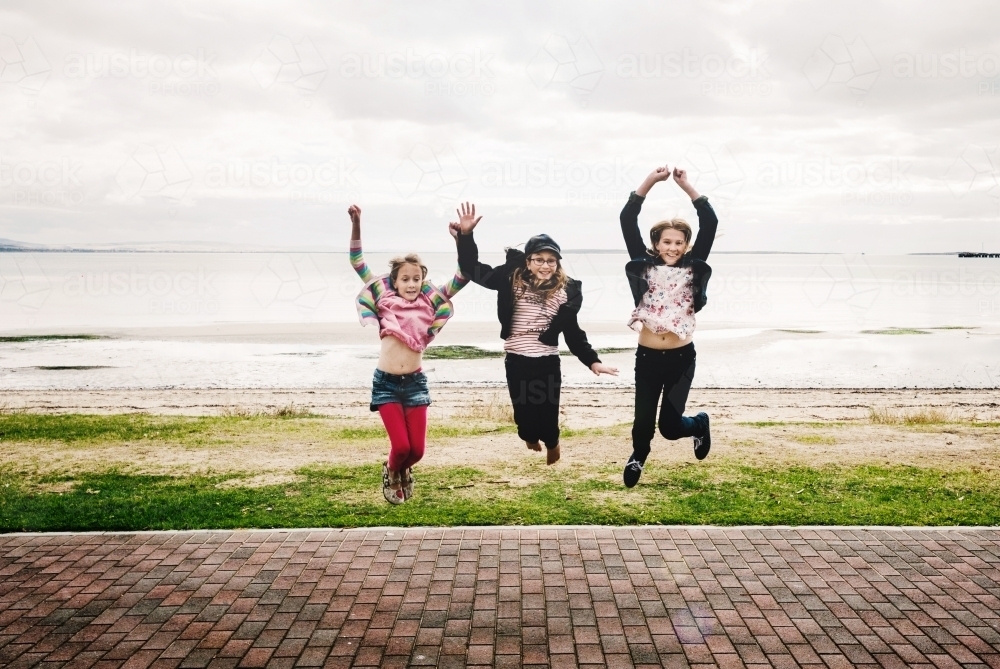 Three girls jumping by the sea - Australian Stock Image