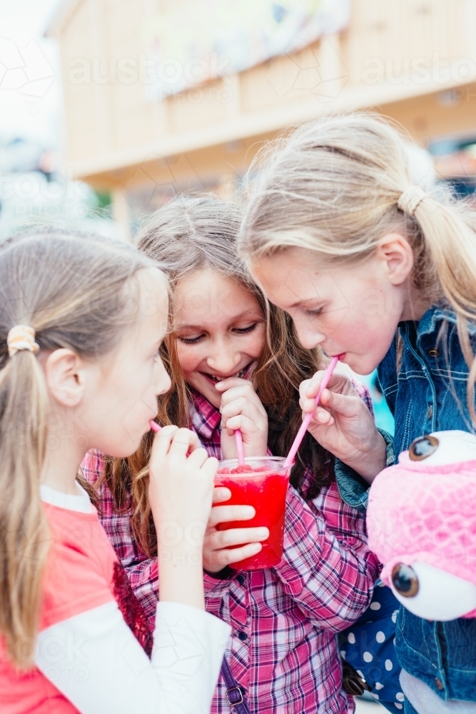 three girls sharing a slushie drink - Australian Stock Image