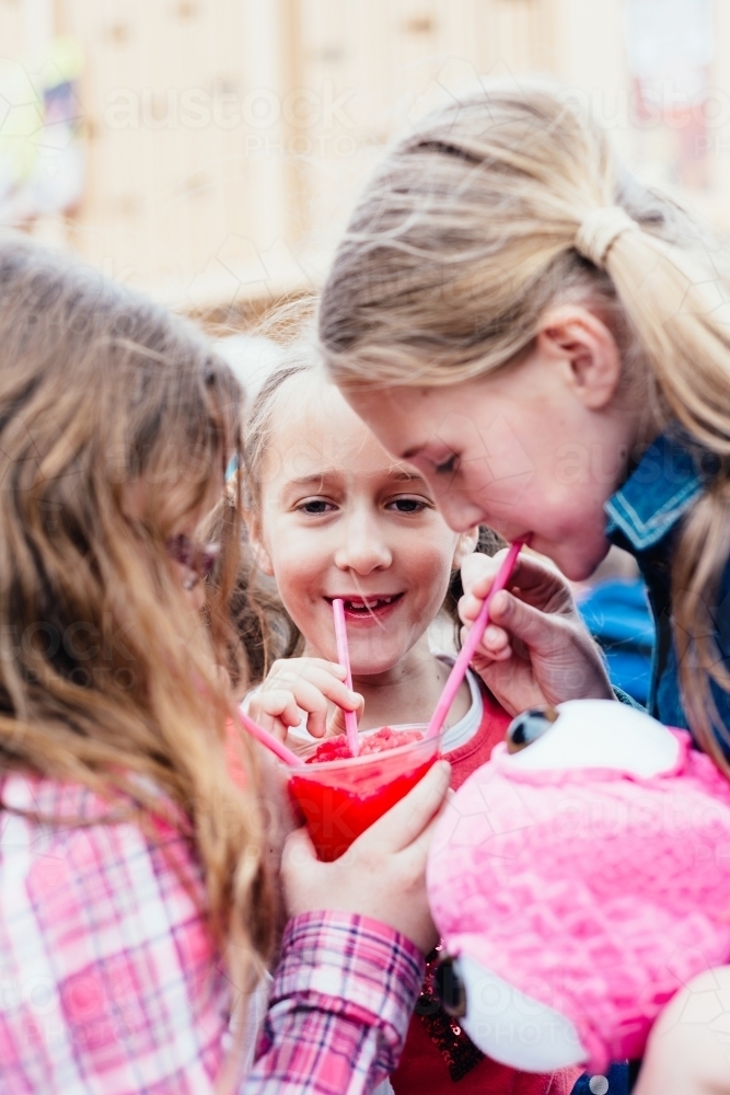 three girls sharing a slushie drink - Australian Stock Image