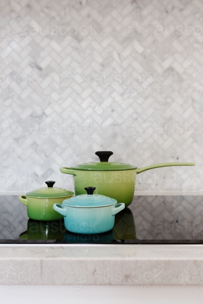 Three green and blue pots arranged on display on a stove - Australian Stock Image