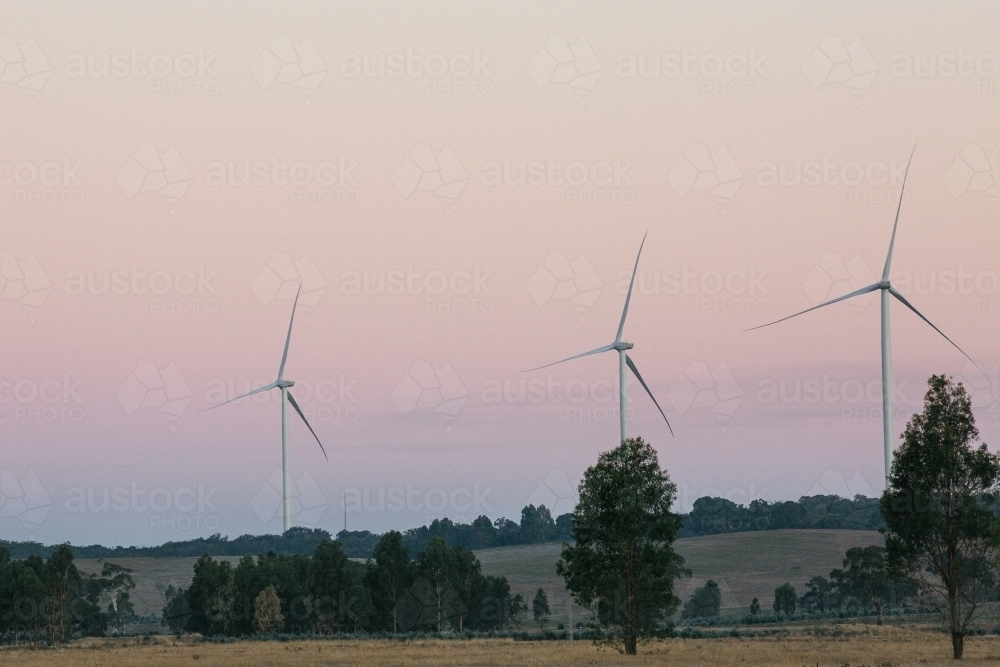 Three green energy wind turbines in the countryside at dusk - Australian Stock Image