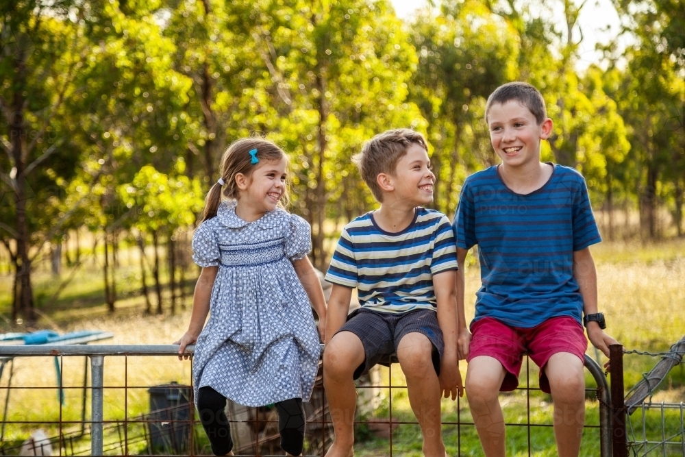 Three happy children laughing together outside - Australian Stock Image