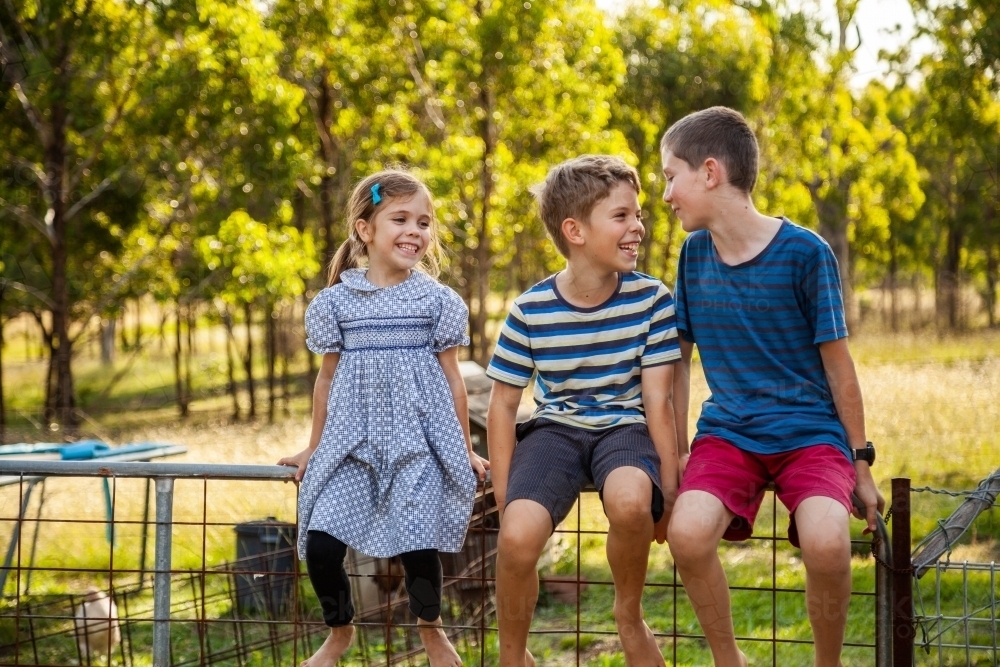 Three happy children laughing together outside - Australian Stock Image