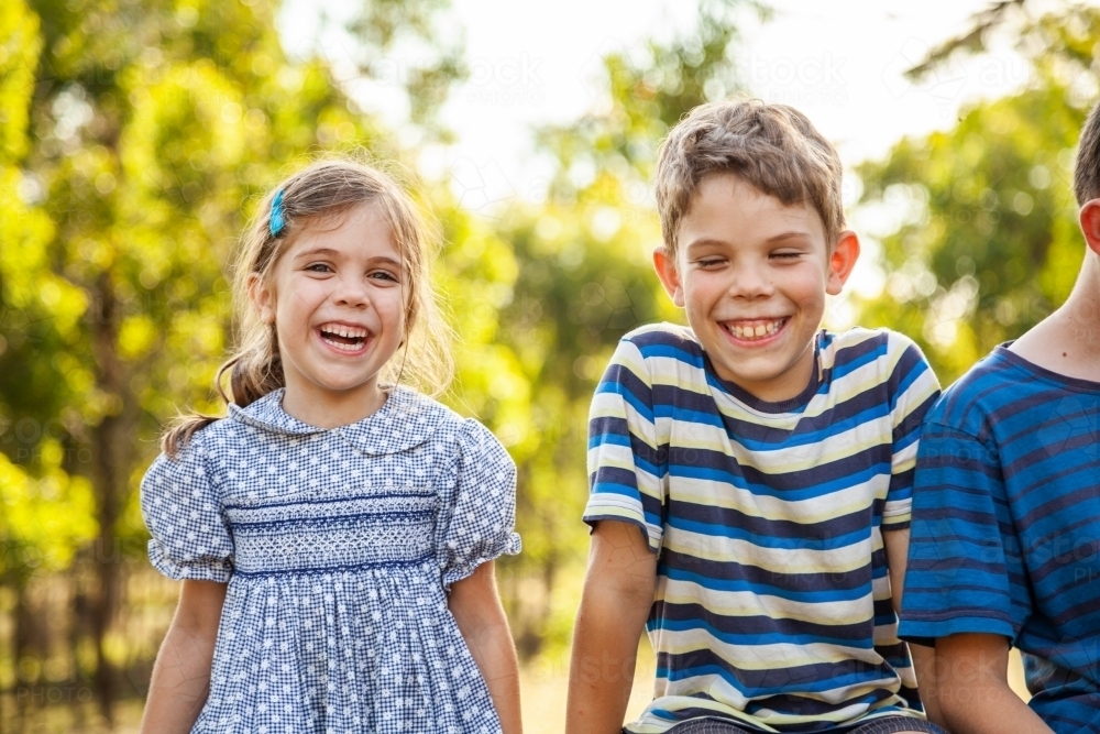 Three happy children laughing together outside - Australian Stock Image