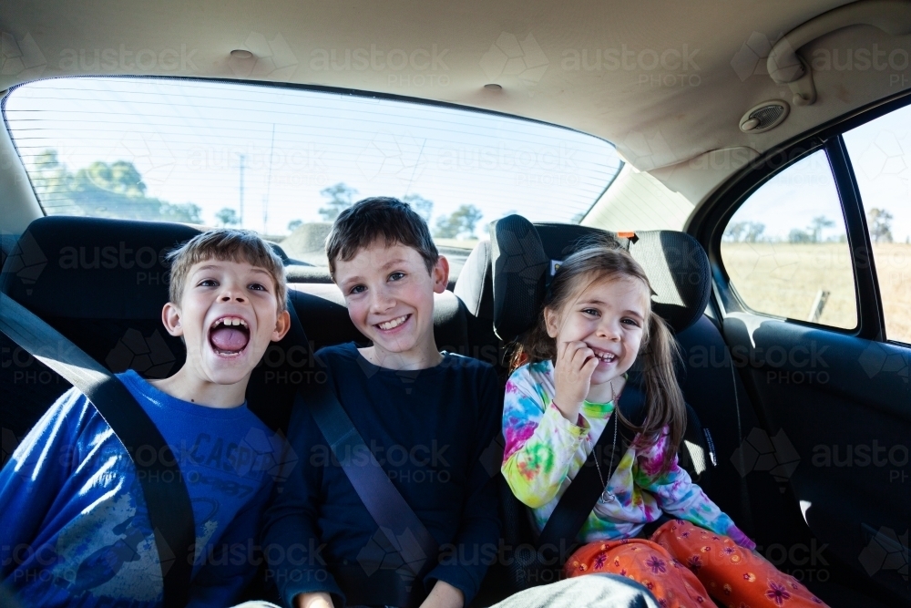 Three happy siblings in the back of a car - Australian Stock Image