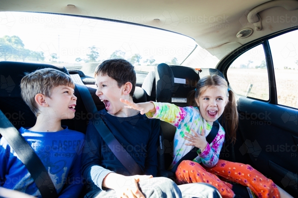 Three happy siblings in the back of a car - Australian Stock Image