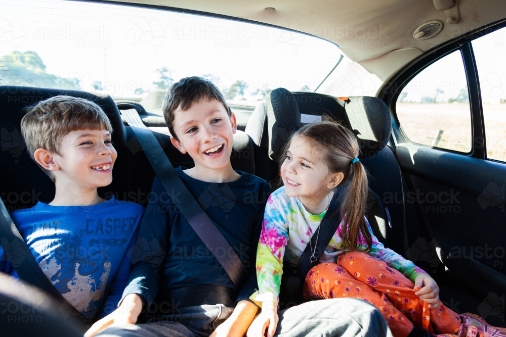 Three happy siblings in the back of a car - Australian Stock Image