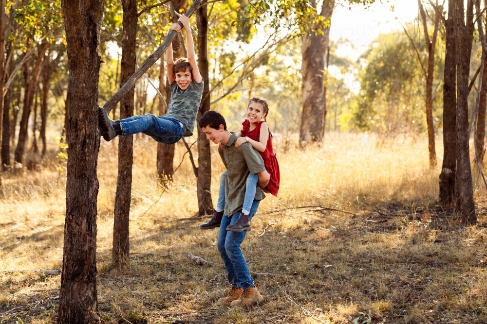 Three happy siblings playing together on country farm in Australia in winter - Australian Stock Image
