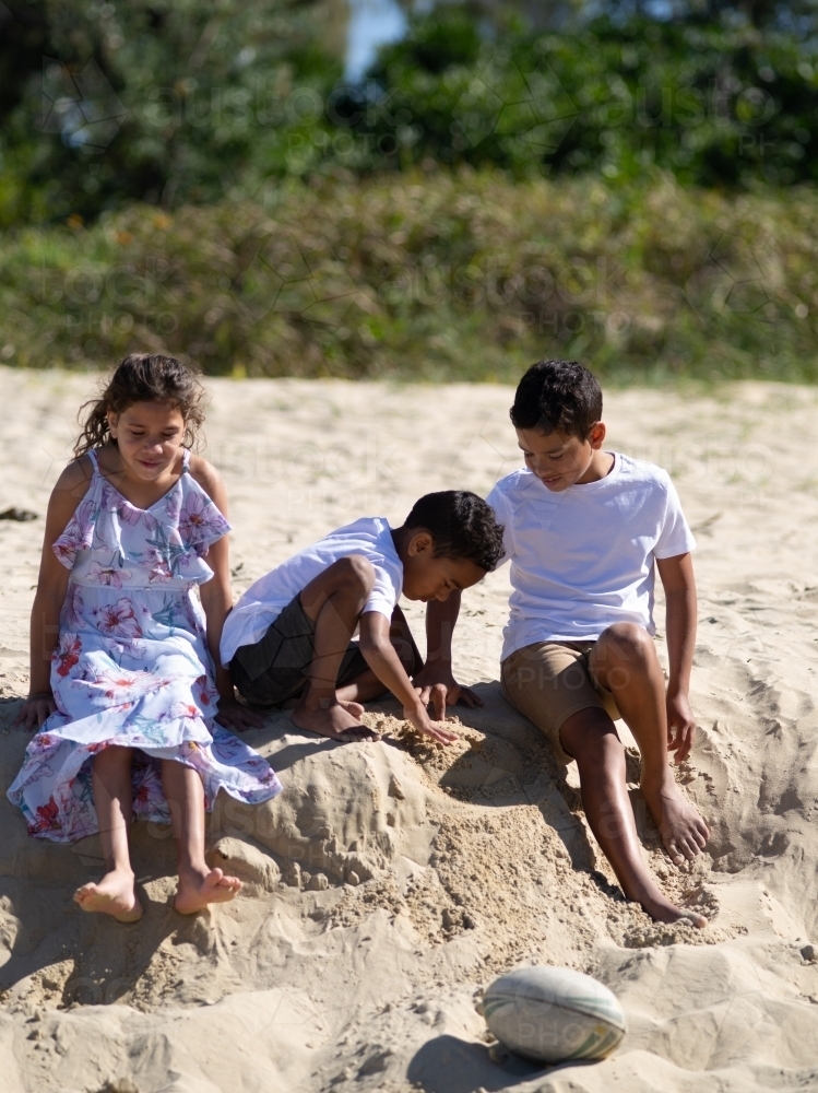 Three indigenous children playing in the sand - Australian Stock Image