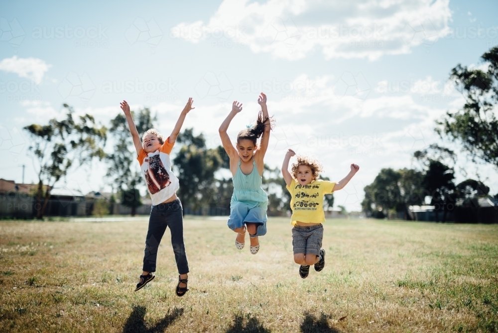 Three kids jumping in the air - Australian Stock Image