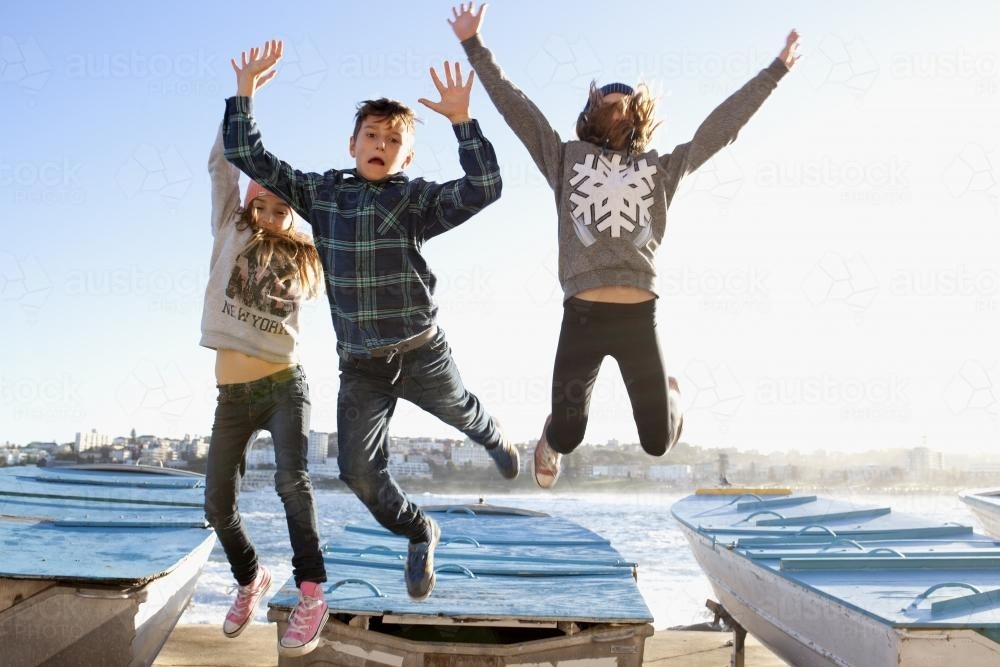 Three kids jumping off a boat in excitement - Australian Stock Image