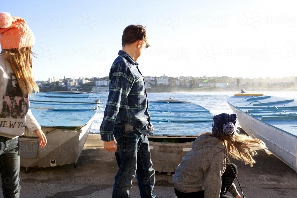 Three kids looking away after jumping off a boat at a boat ramp - Australian Stock Image