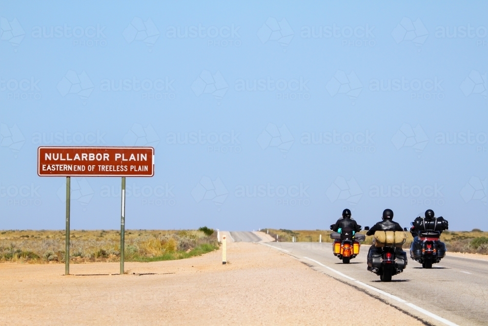 Three motorcycles pass the sign for the eastern end of the Nullarbor Plain - Australian Stock Image
