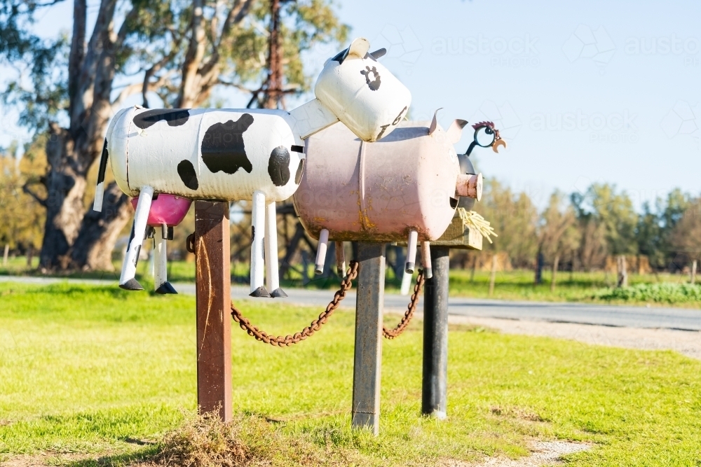 Three novelty letter boxes on posts on the side of a road - Australian Stock Image