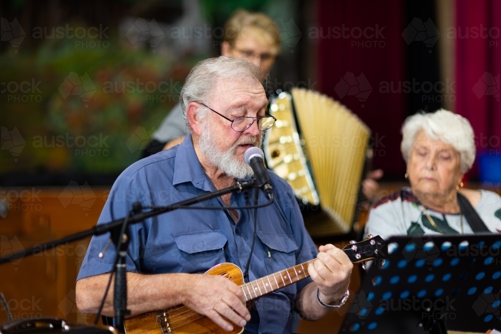 Image of three older people playing music and singing - Austockphoto