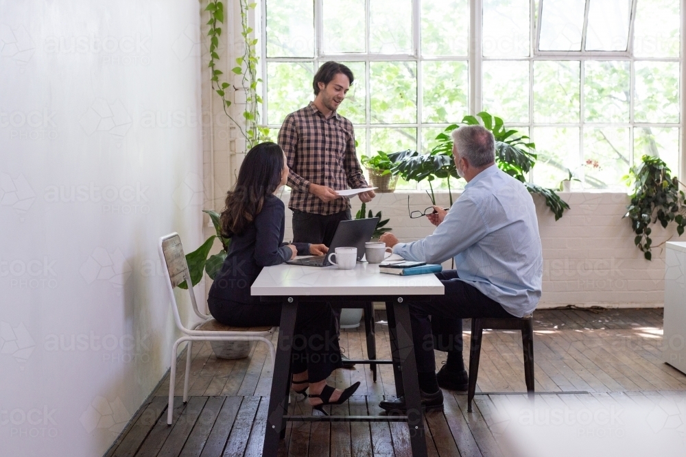 Three people collaborating in an open office - Australian Stock Image