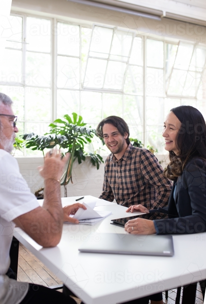Three people sitting, collaborating in an office - Australian Stock Image