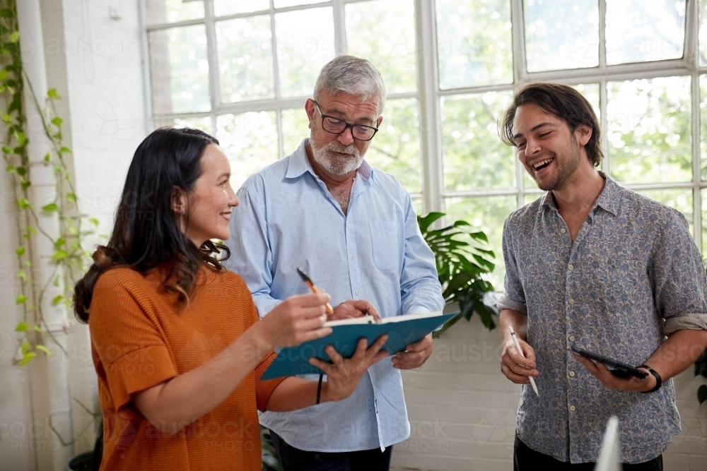 Three professional business people, sharing ideas in a studio office - Australian Stock Image
