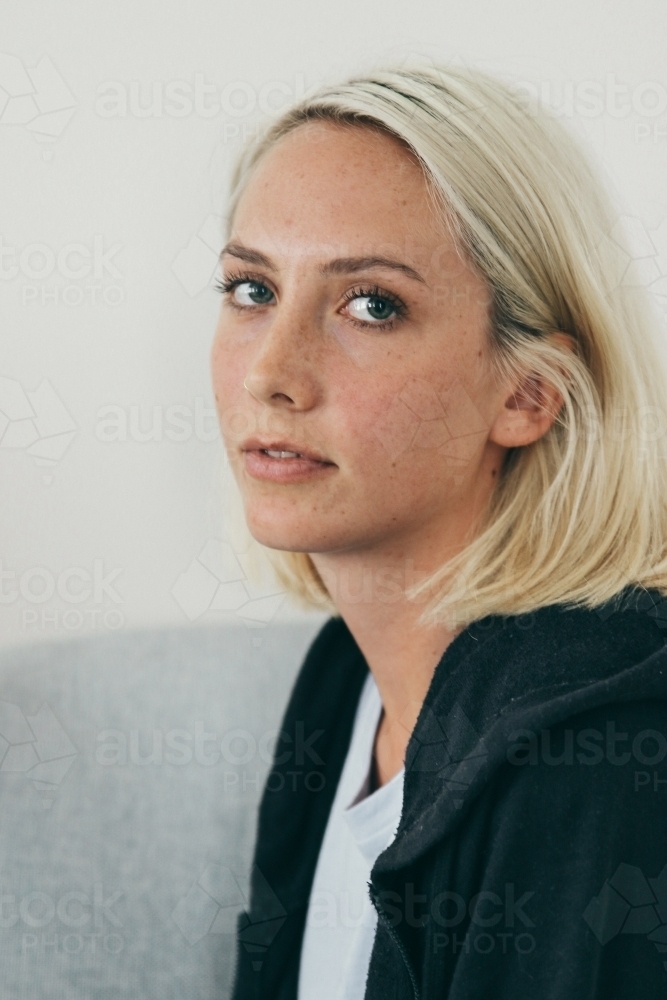 Three quarter profile of young blonde woman in hoodie and tshirt - Australian Stock Image