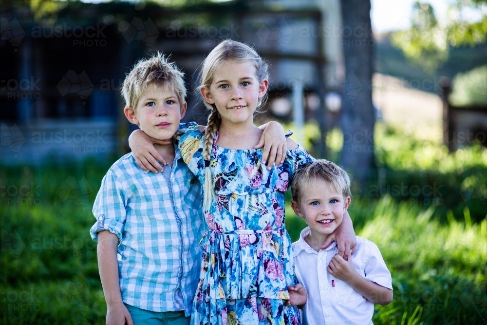three siblings standing together smiling - Australian Stock Image