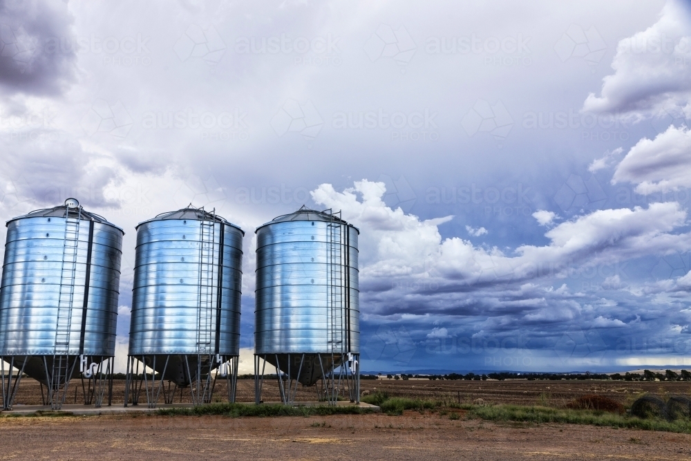 Three silos and farm land with storm clouds - Australian Stock Image