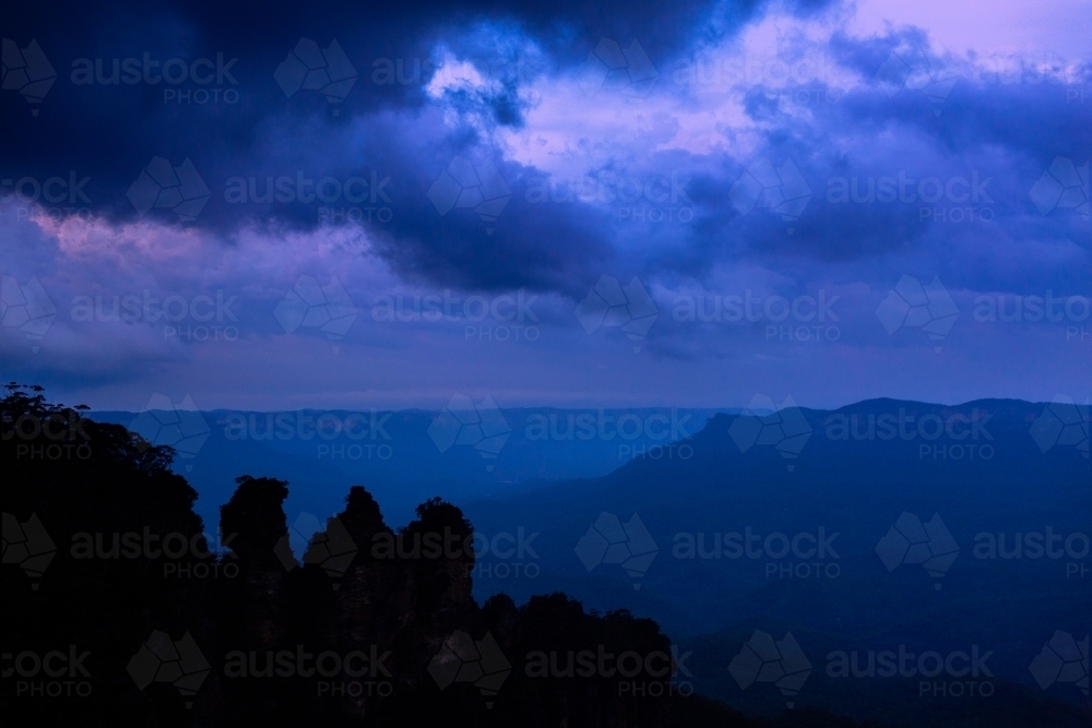 Three sisters in silhouette at dusk with storm clouds filling sky - Australian Stock Image