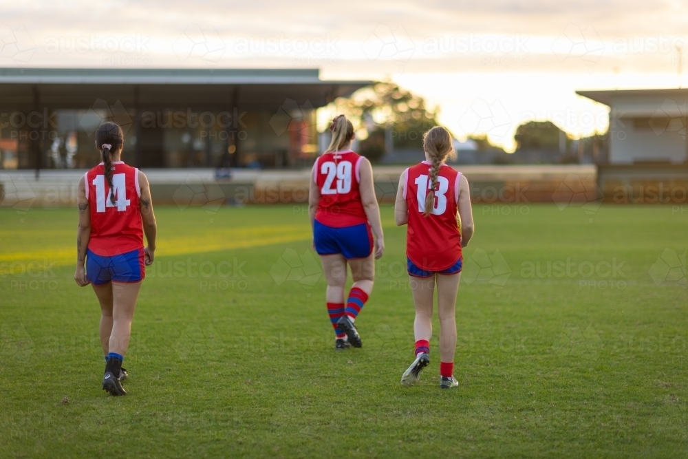 three teammates walking off the oval after a game of aussie rules football - Australian Stock Image