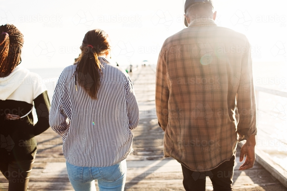 Three teenage friends walking along a jetty - Australian Stock Image