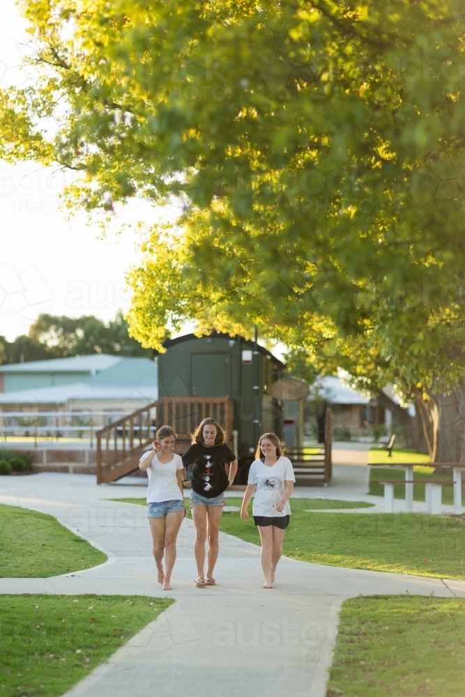 Three teenage friends walking on a concrete path - Australian Stock Image