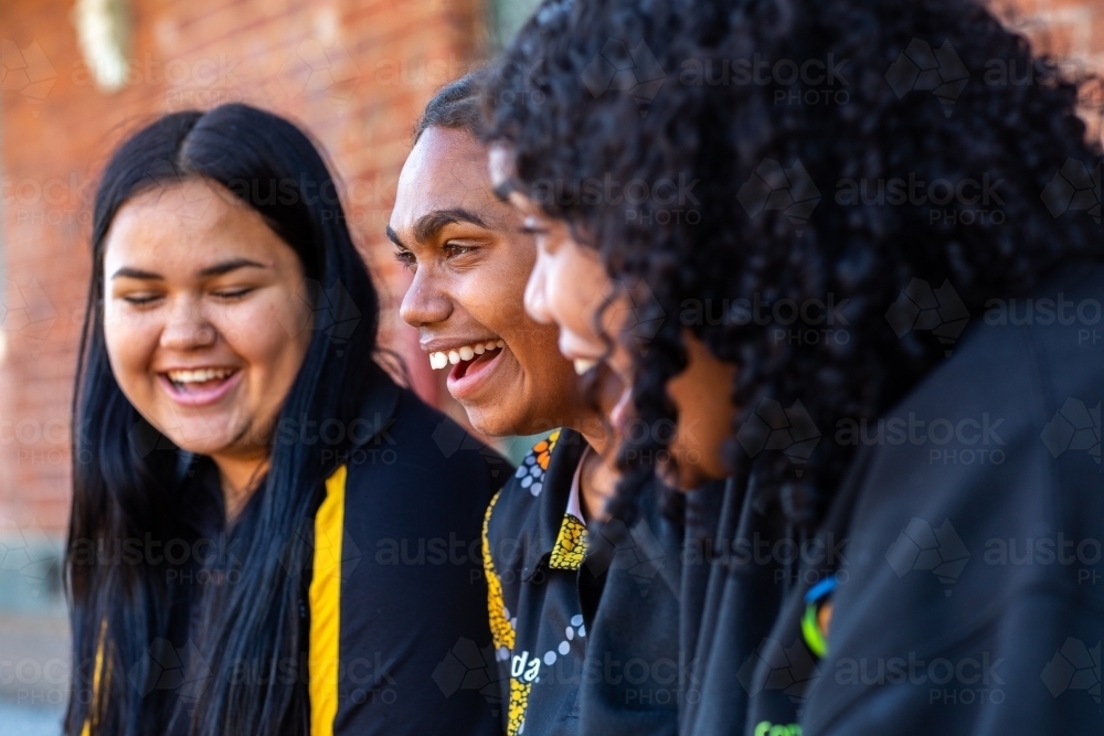 three teenage girls in black laughing together - Australian Stock Image