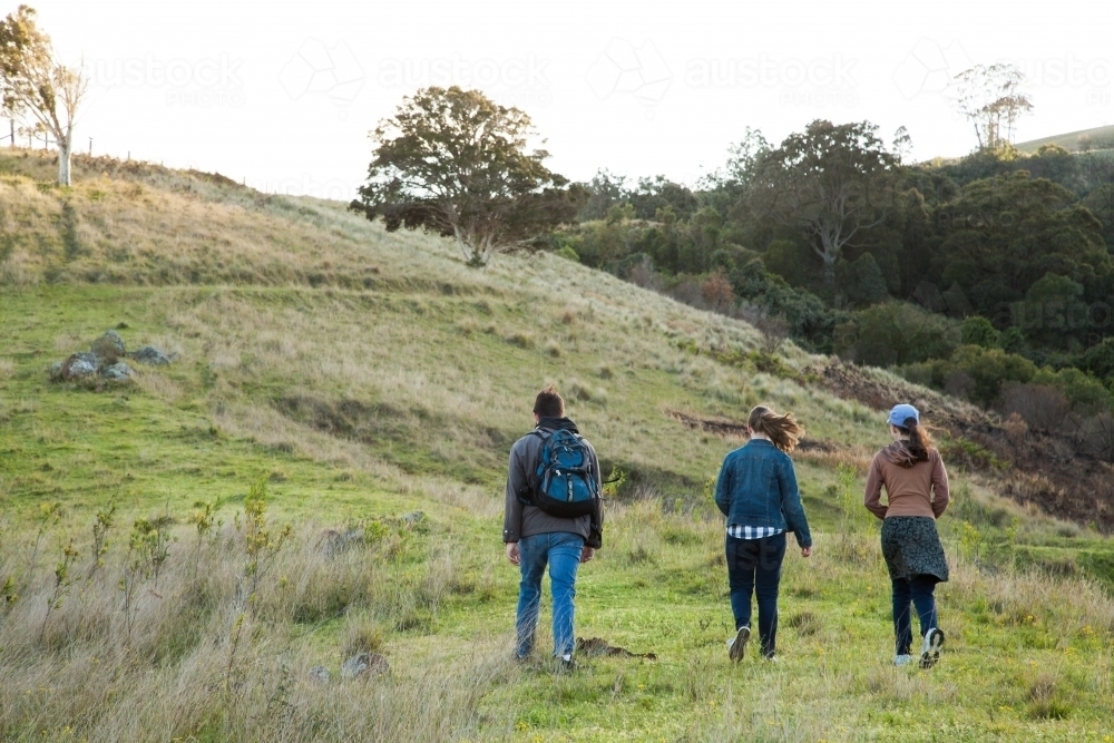 Three teens walking up a hill on a windy morning - Australian Stock Image
