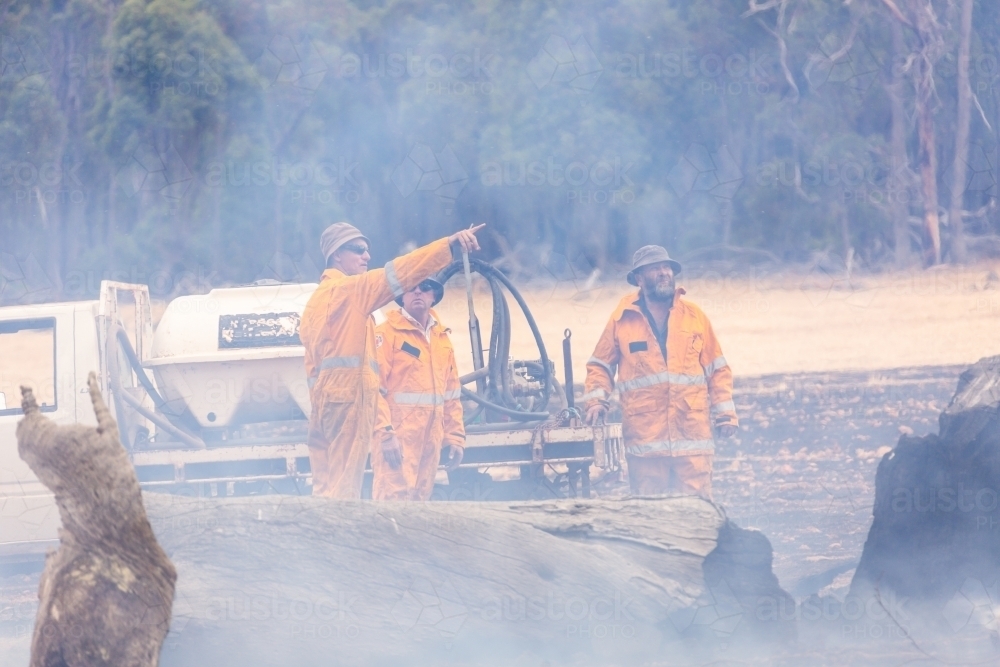 Three volunteer firefighters standing in smokey setting after fire - Australian Stock Image