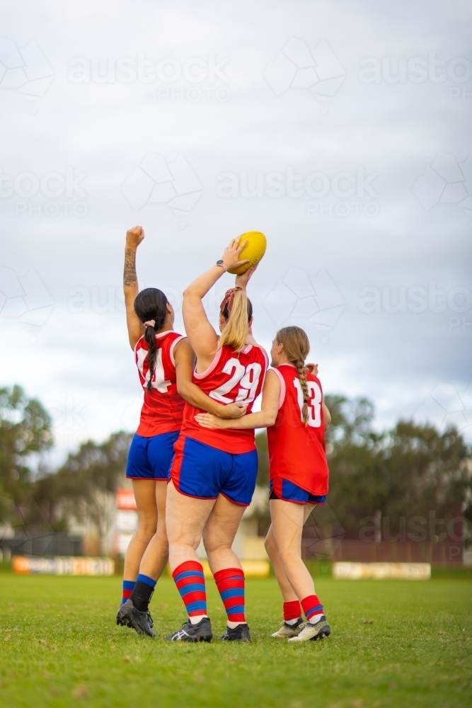 three women football players celebrating with the ball held aloft - Australian Stock Image