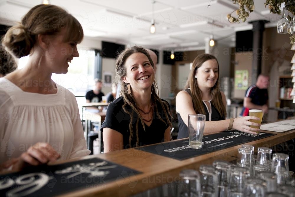 Three women having a drink at the bar of local craft beer bar - Australian Stock Image