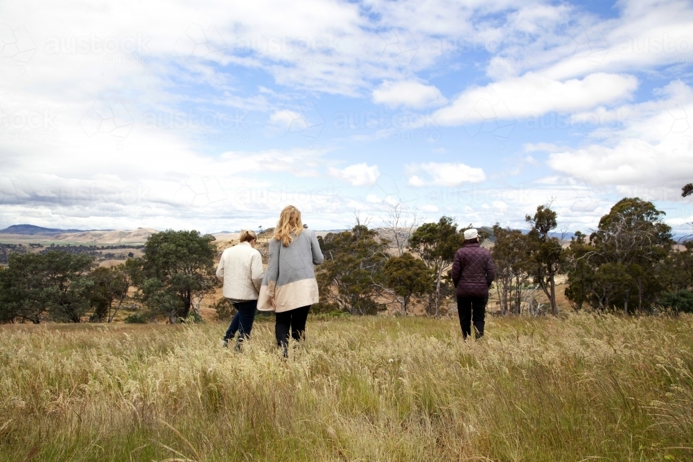 Three women walking off into the distance on a farm - Australian Stock Image