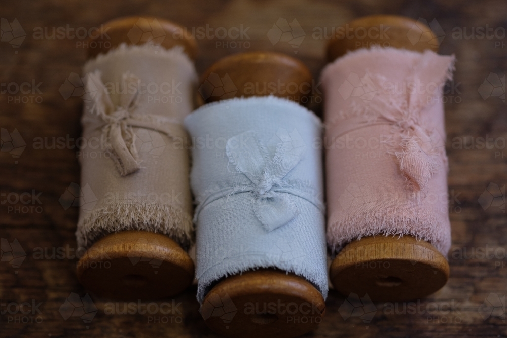 Three wooden vintage ribbon spools on a country table - Australian Stock Image