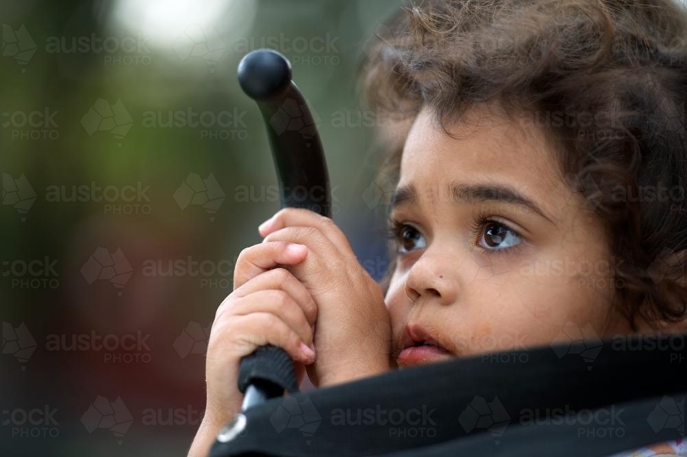 Three Year Old Aboriginal Girl Holding Pusher Handle - Australian Stock Image