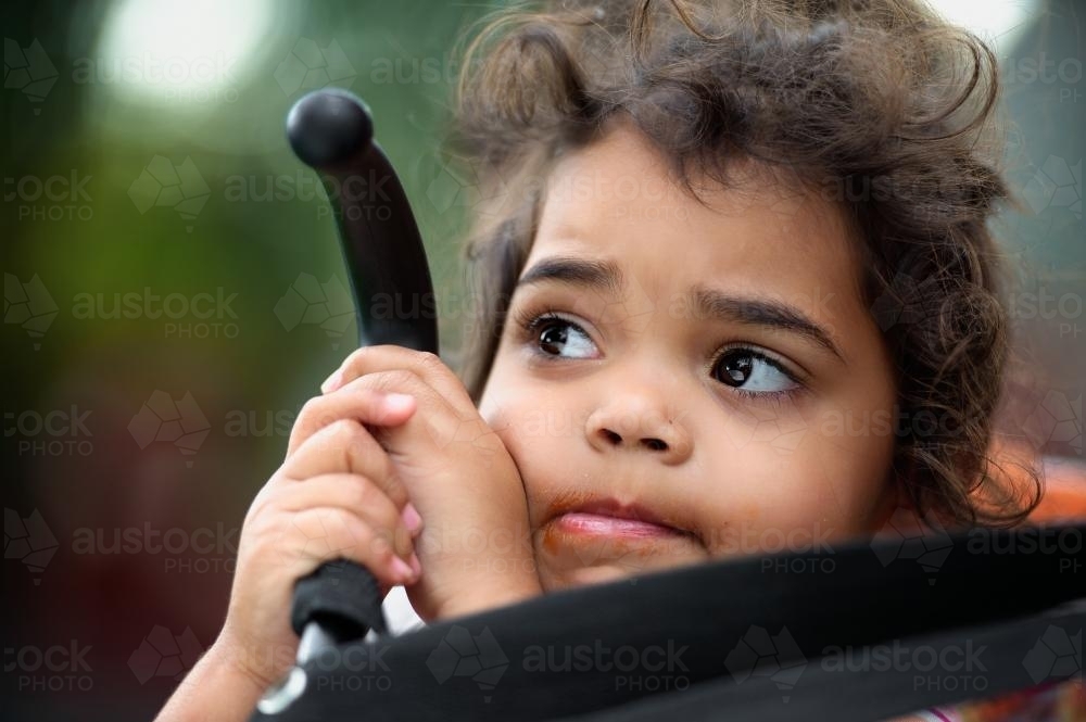 Three Year Old Aboriginal Girl with Two Hands Holding Pusher - Australian Stock Image